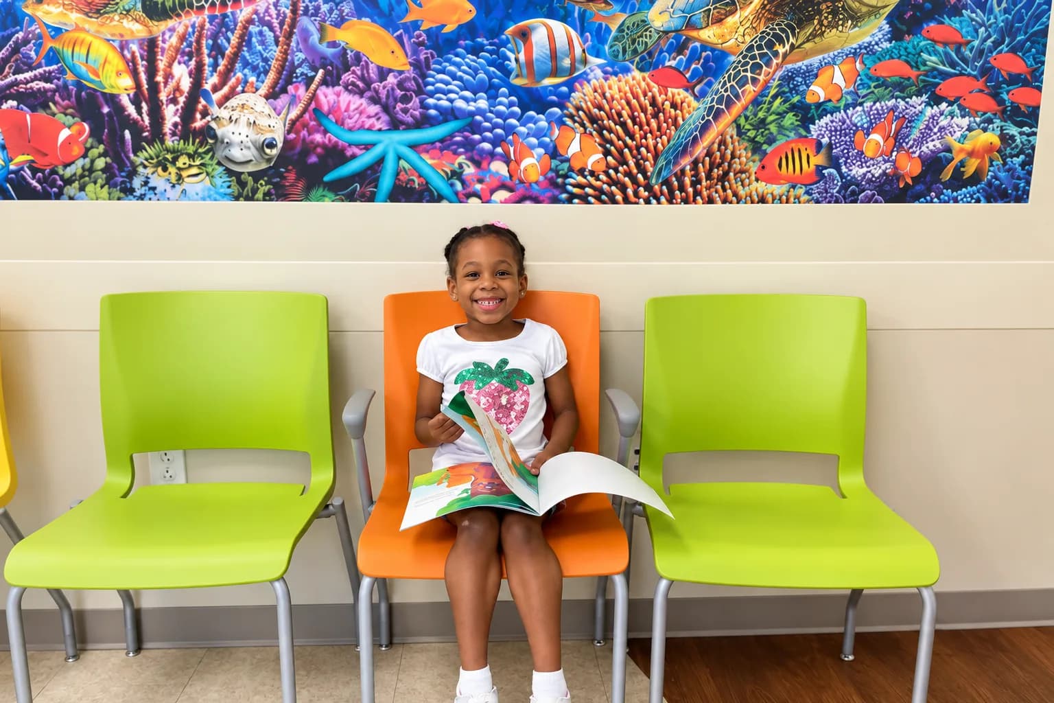 Young girl reading a book in the waiting room before her well child visit